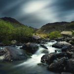 time lapse photo of riverbed and lush grass field during cloudy day
